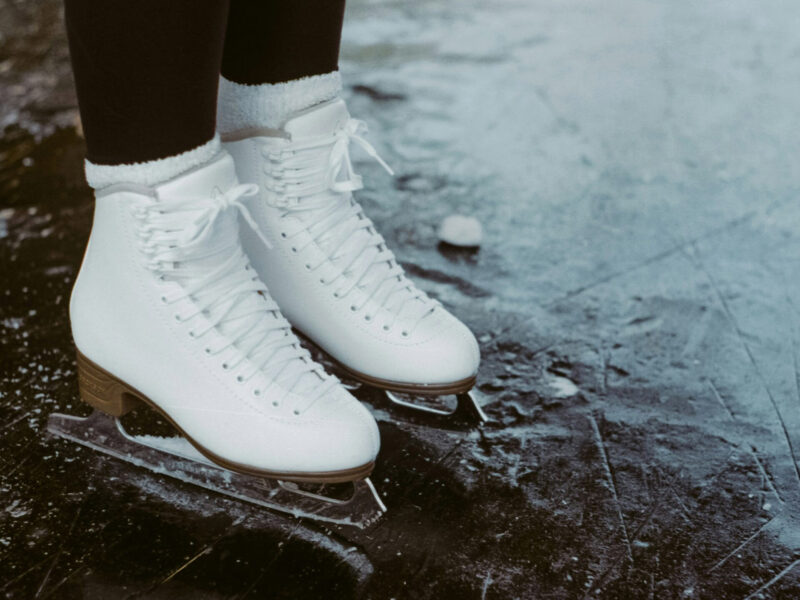 A person wearing figure skates standing on a frozen pond