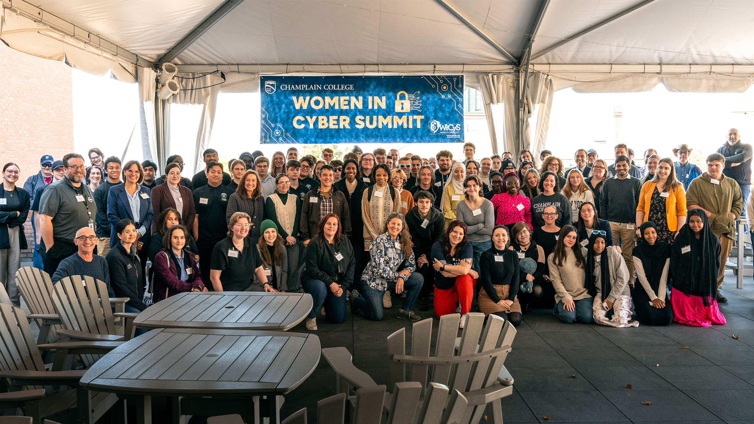 big group of people under a sign that reads "women in cyber summit"
