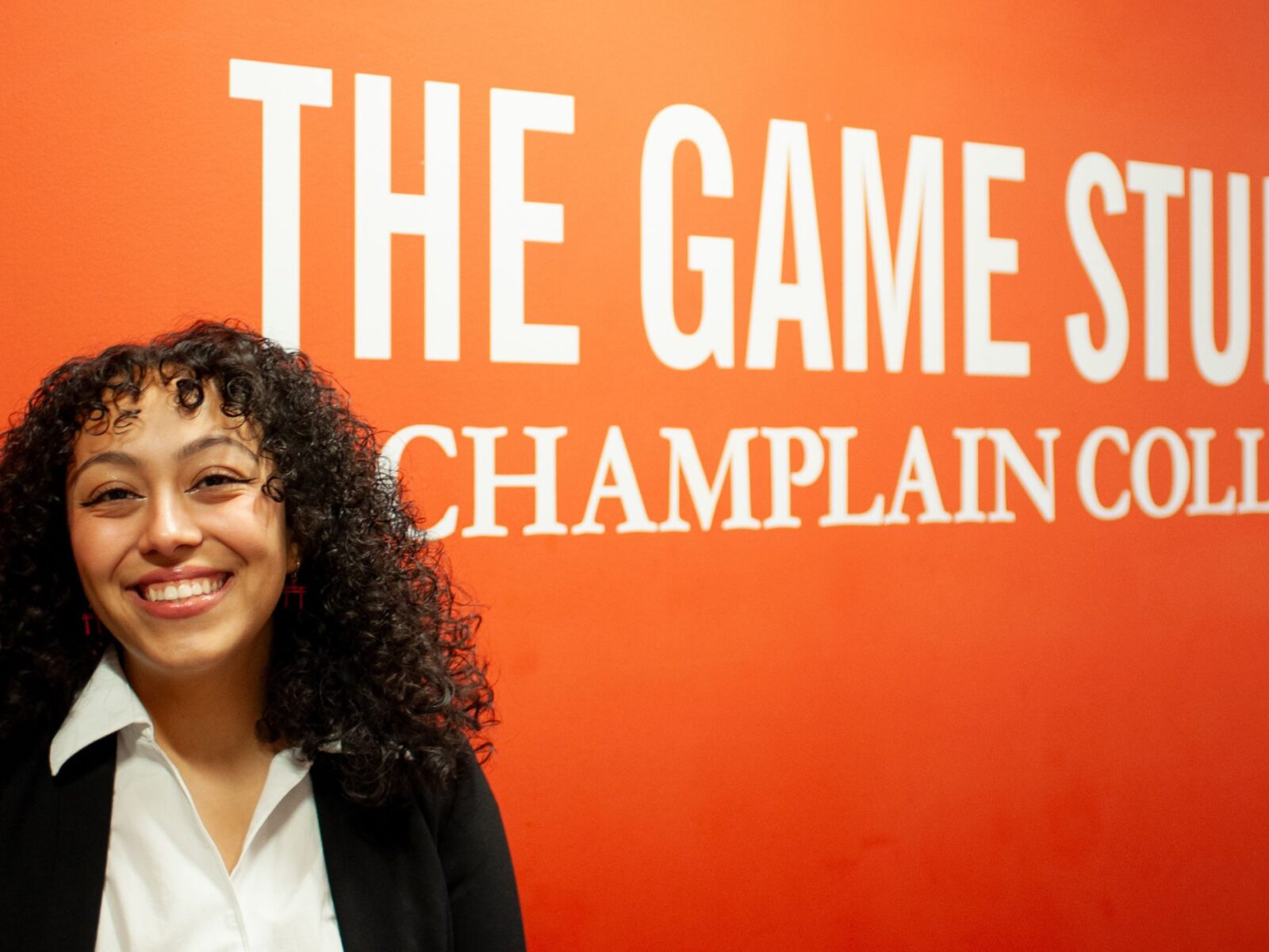 Zoe Campos in front of the game studio orange painting on campus