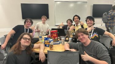 A group of game design students pose for the camera in the midst of a game-making contest.