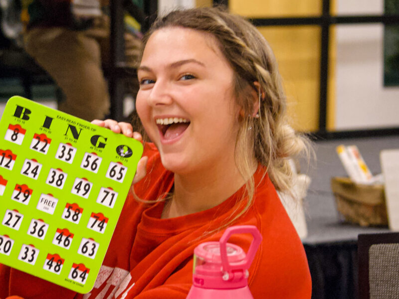 student smiling and holding a bingo card