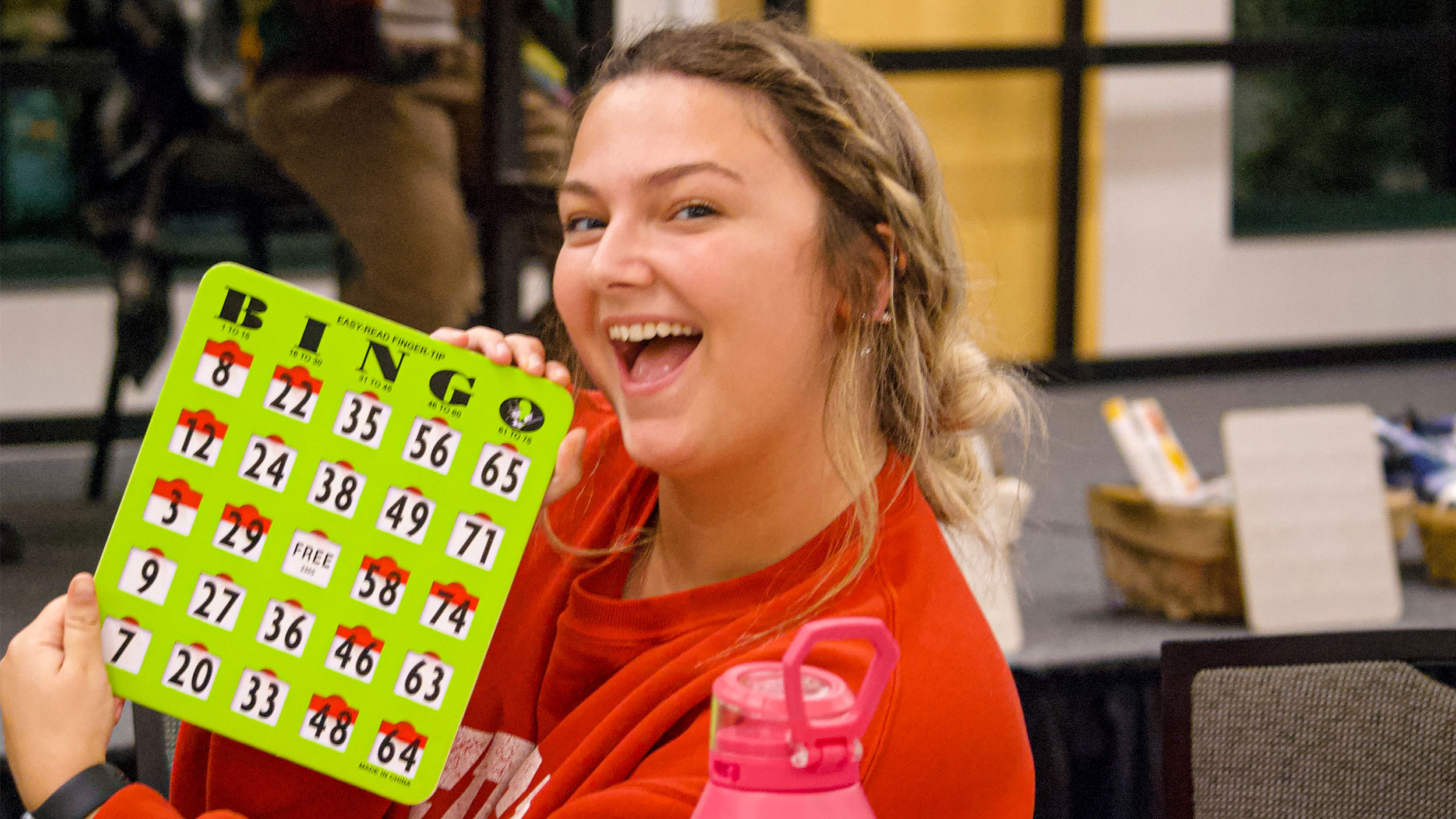student smiling and holding a bingo card