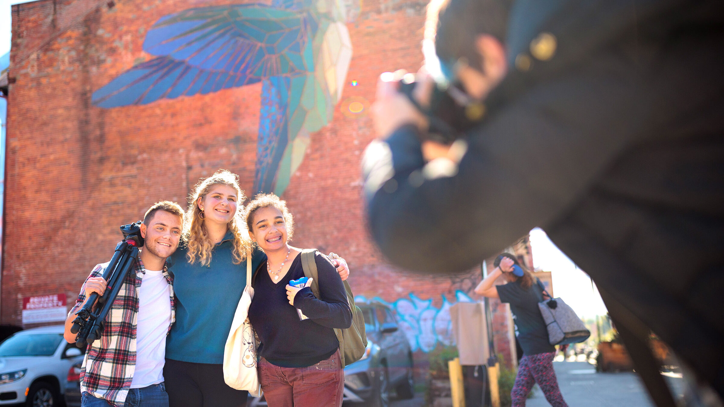 Champlain students pose for a photo, hummingbird mural behind them