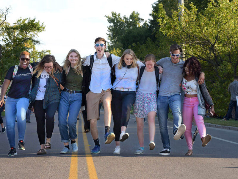 a group of students walking in a line across a street with their arms linked together behind their backs