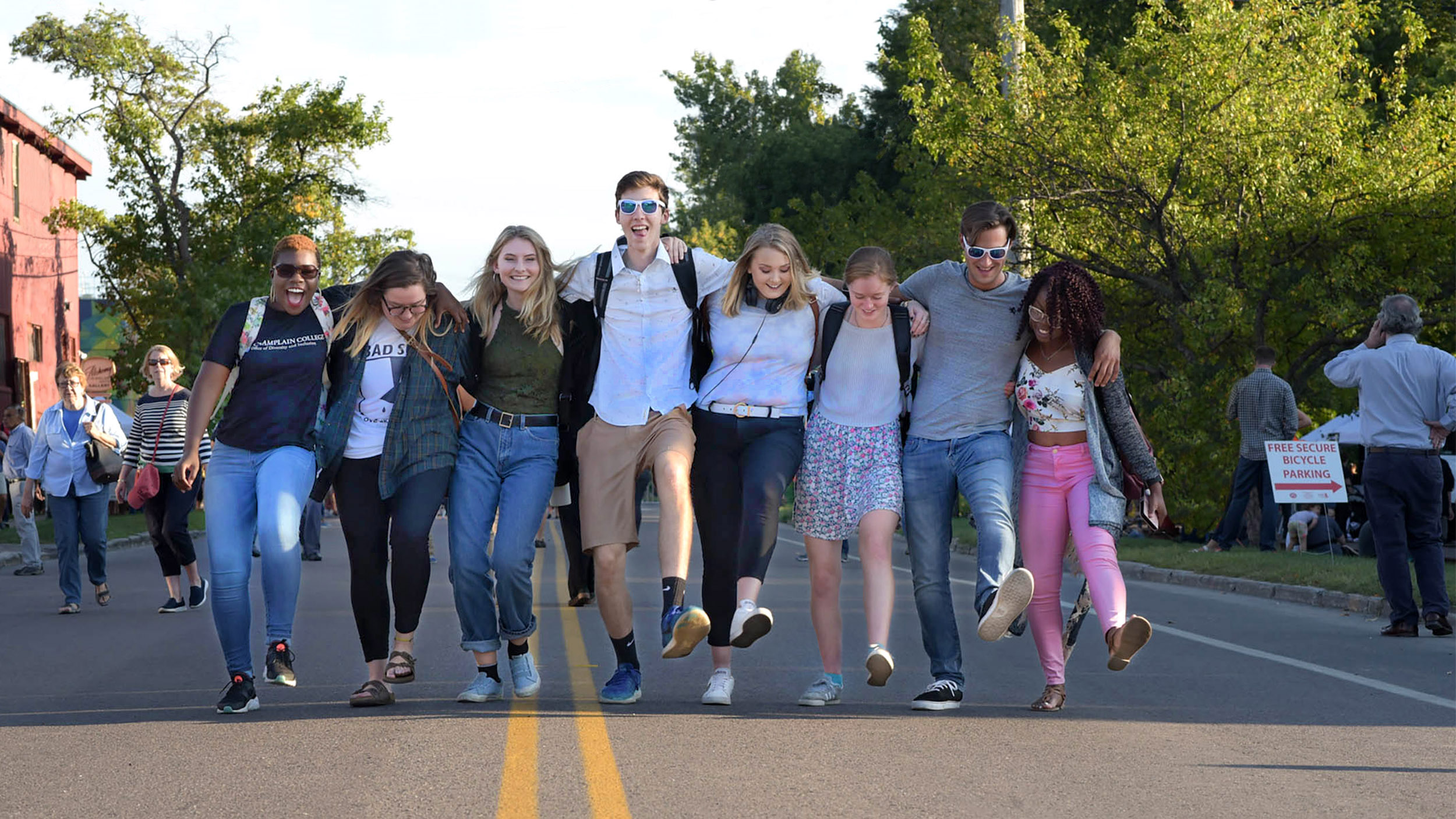 a group of students walking in a line across a street with their arms linked together behind their backs