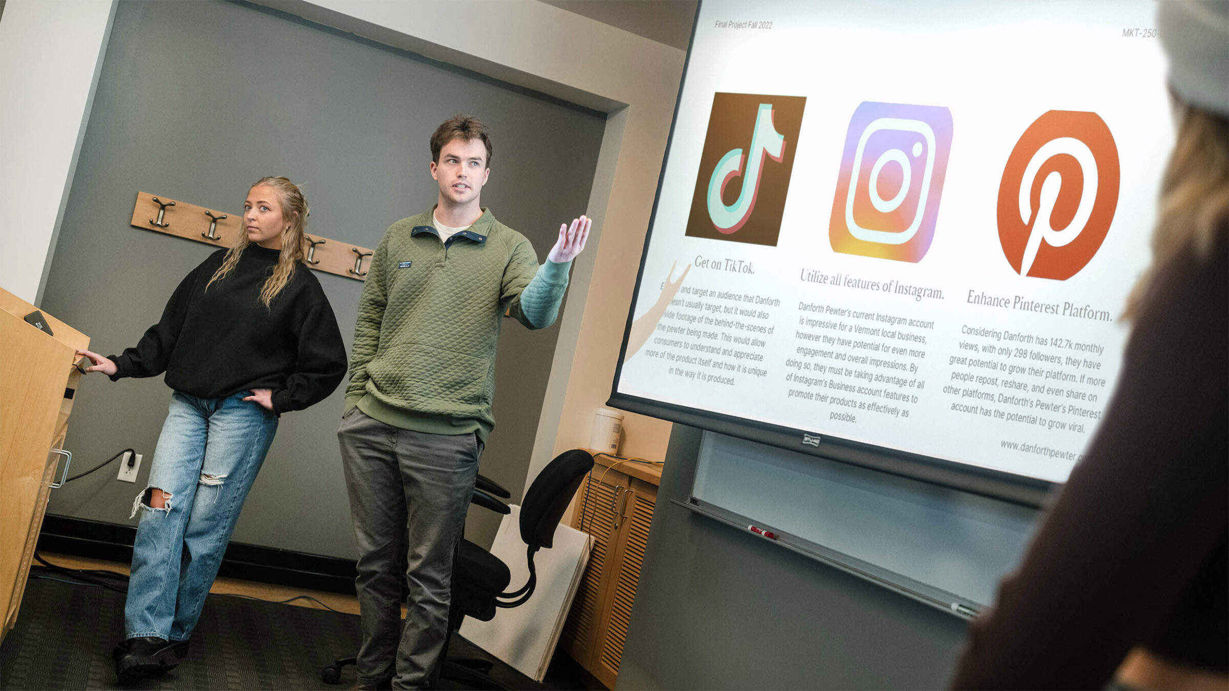 two students present their work to the class via a slide presentation