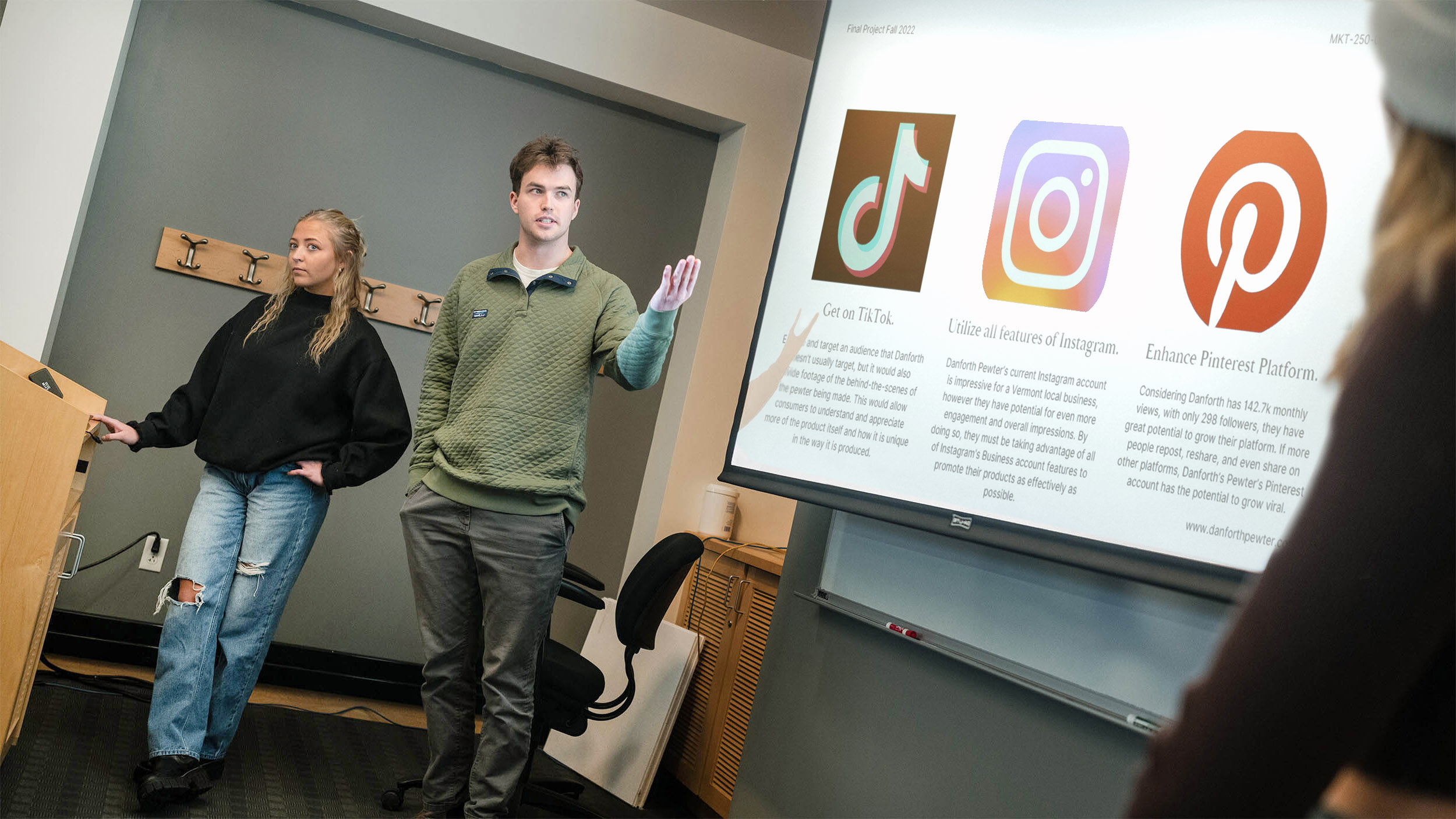 two students present their work to the class via a slide presentation