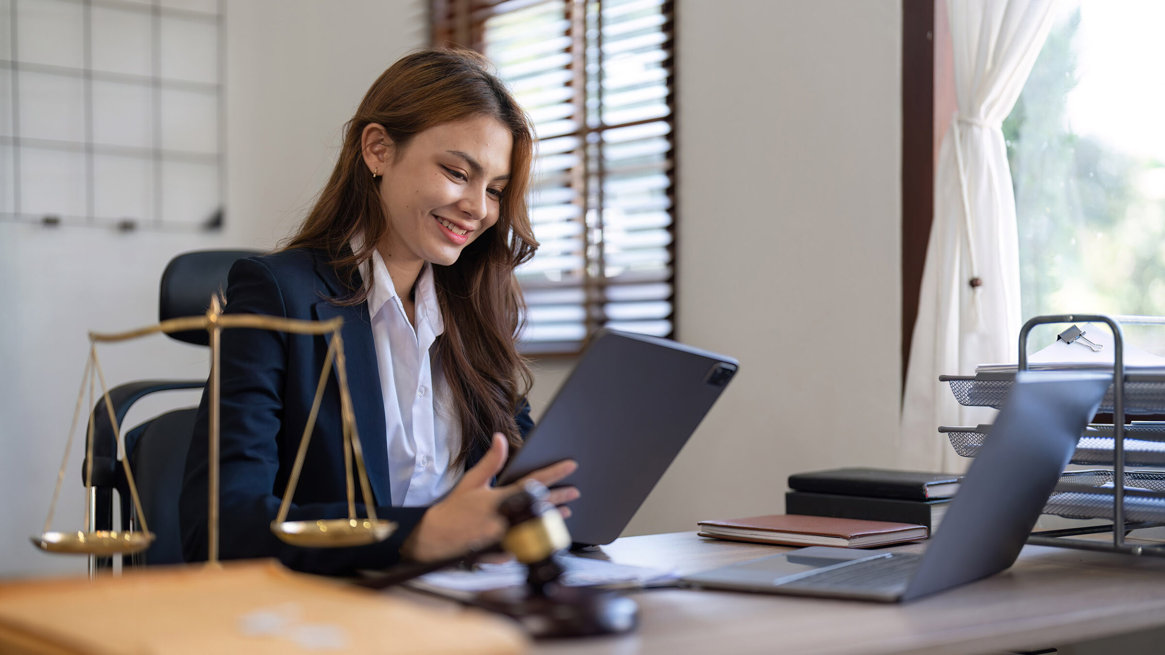young lawyer in office with brass scale on wooden desk in office. Law, legal services, advice, Justice and real estate concept.