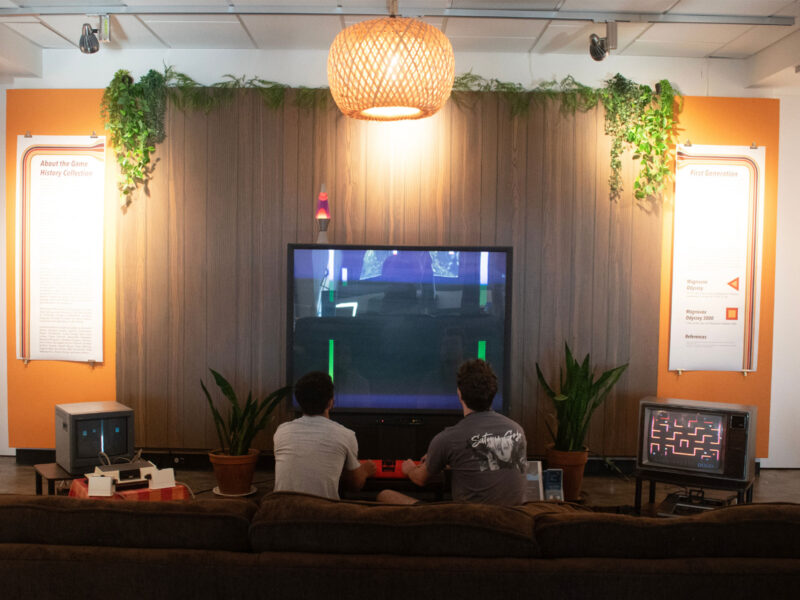 two students sit on a couch playing a video game in the art gallery