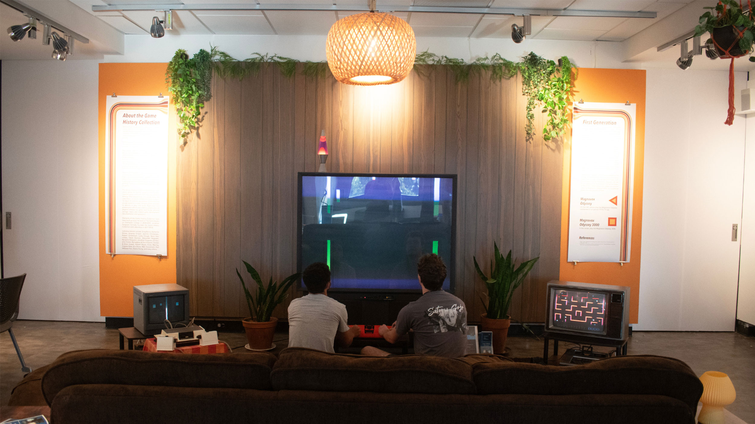 two students sit on a couch playing a video game in the art gallery