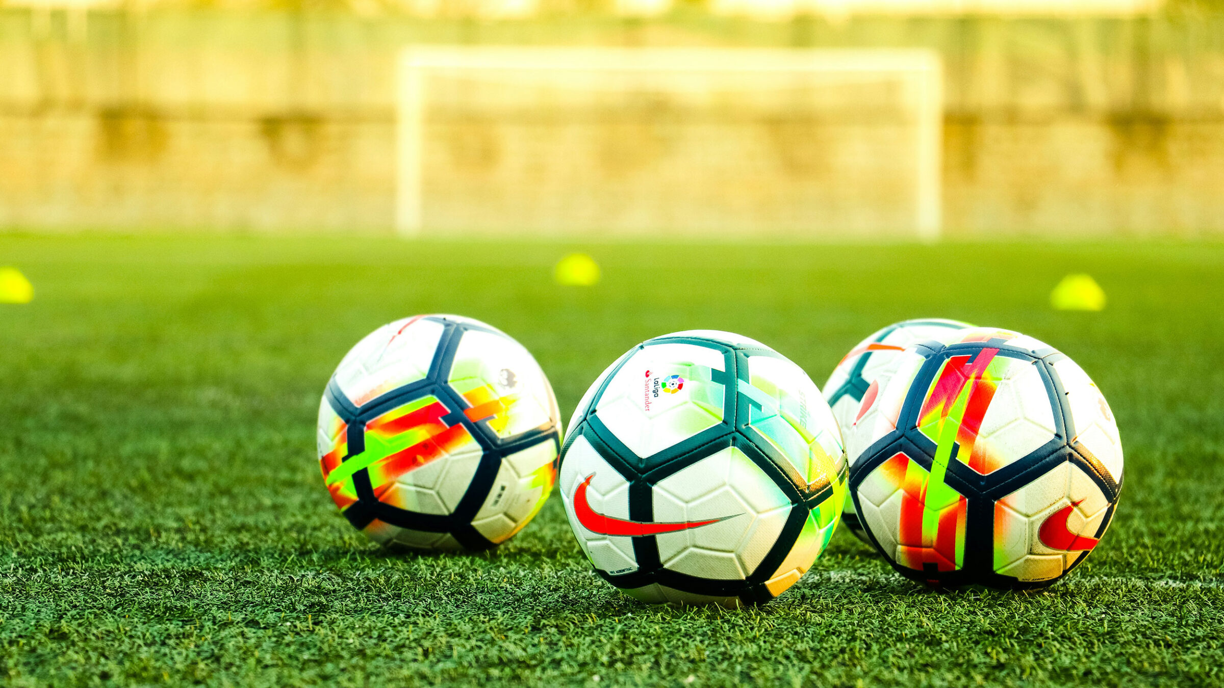 three soccer balls on a grassy soccer field