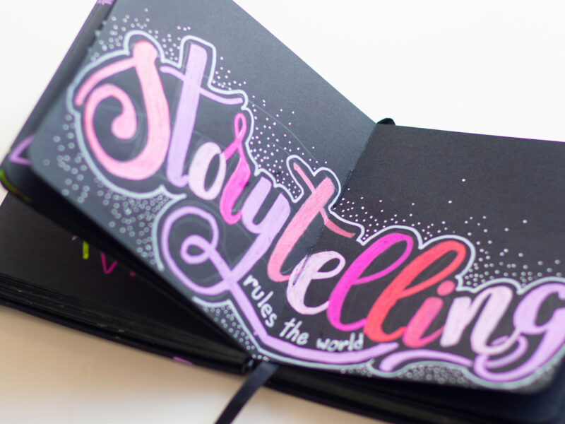 notebook that reads "storytelling" in pink letters