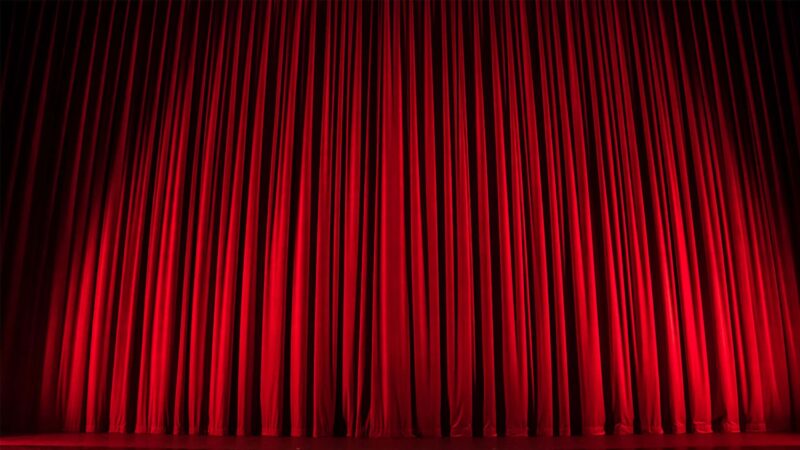 Red curtains on a stage lit by a spotlight