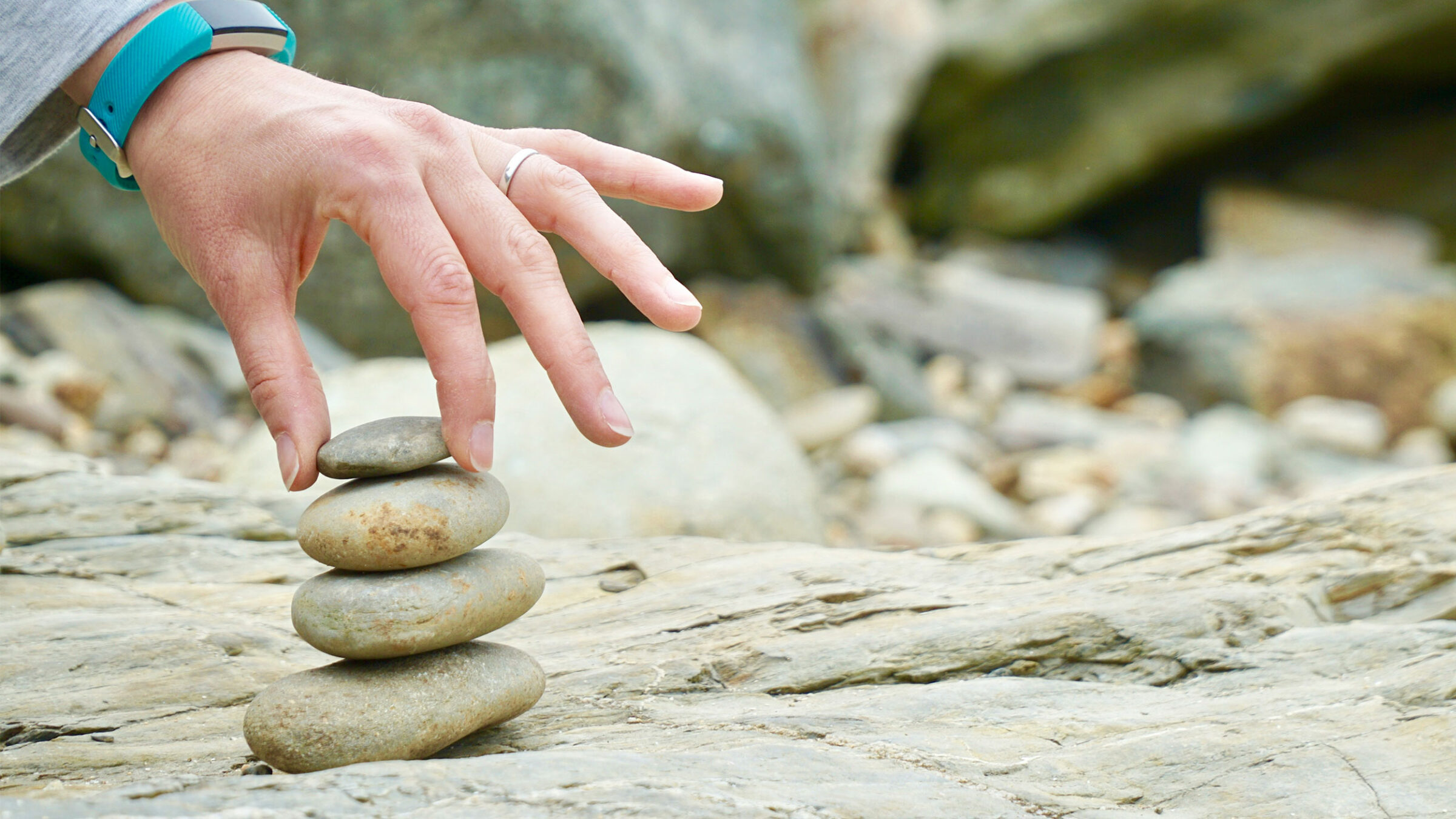 a hand touches a small tower of 4 rocks