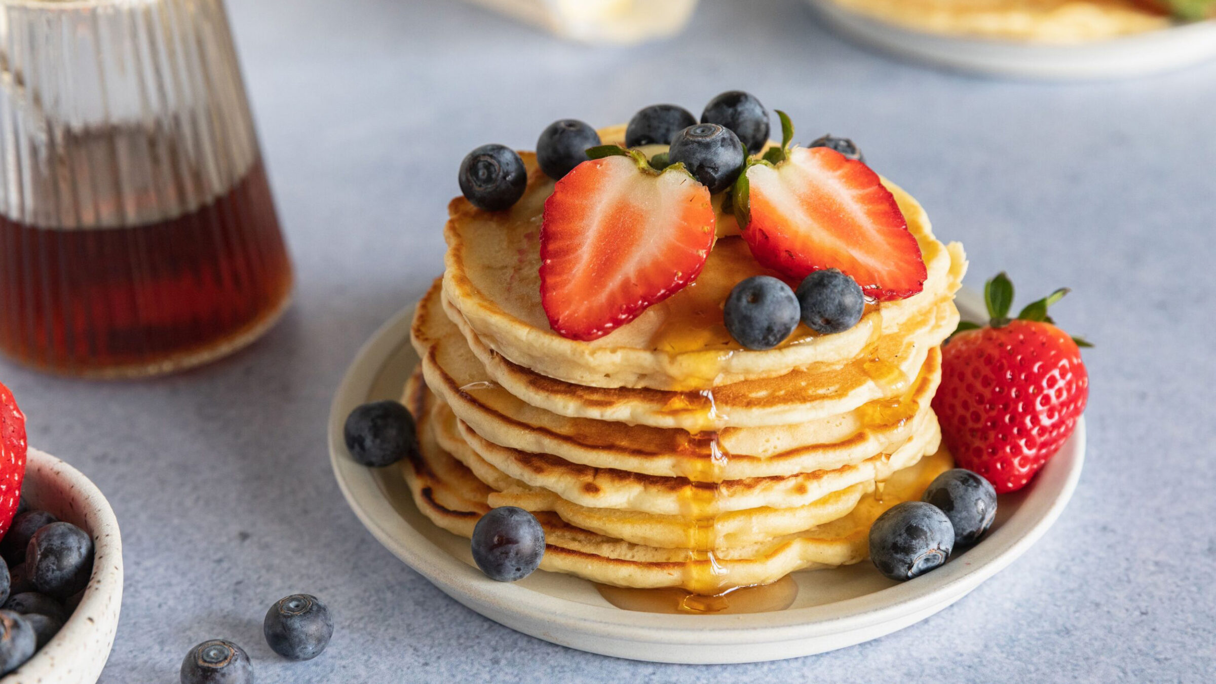A stack of pancakes on a table with fruit