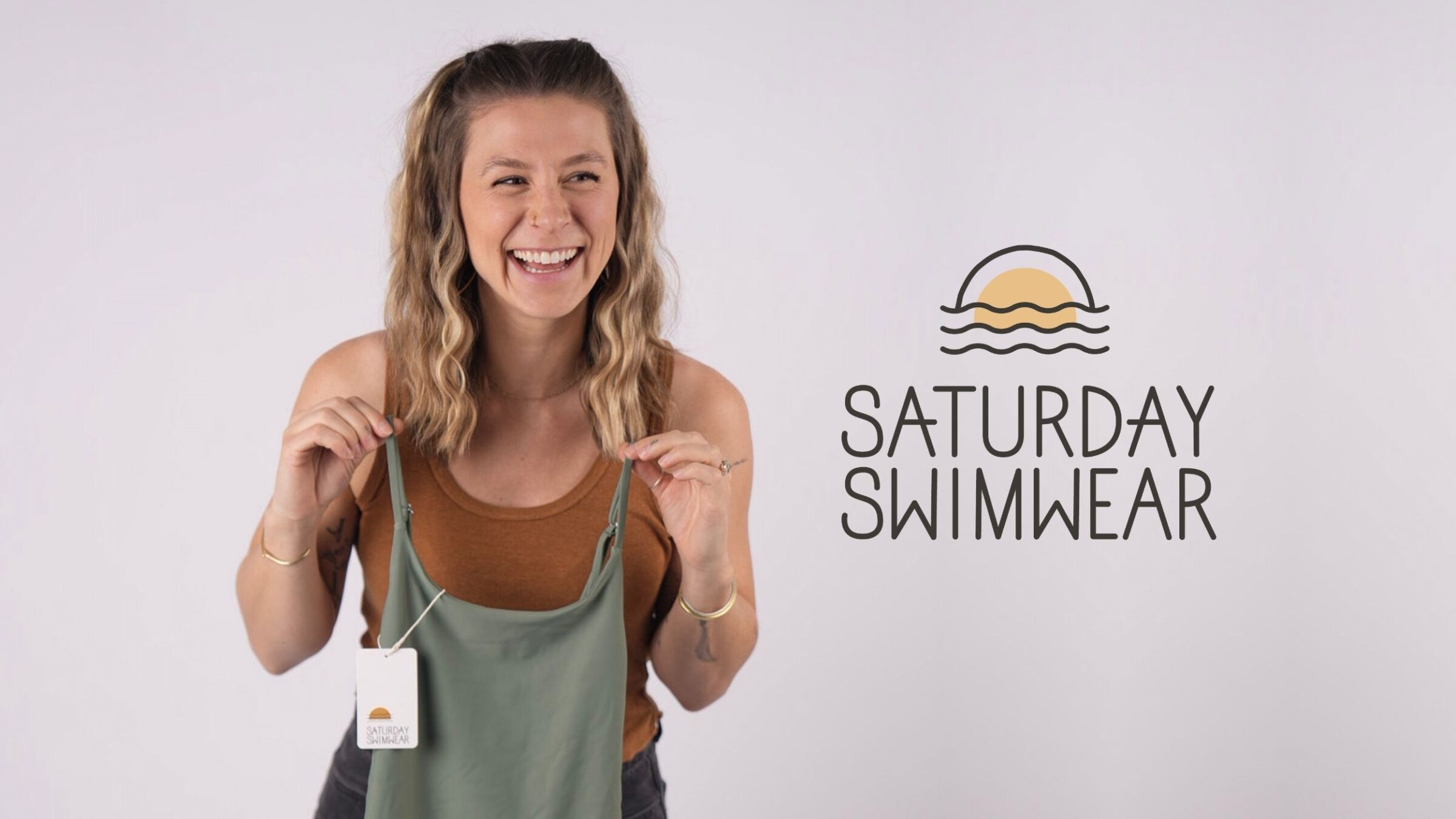 Emily holding a swimsuit next to the Saturday Swimwear logo