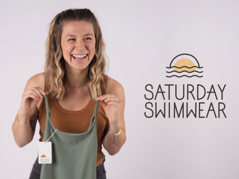 Emily holding a swimsuit next to the Saturday Swimwear logo