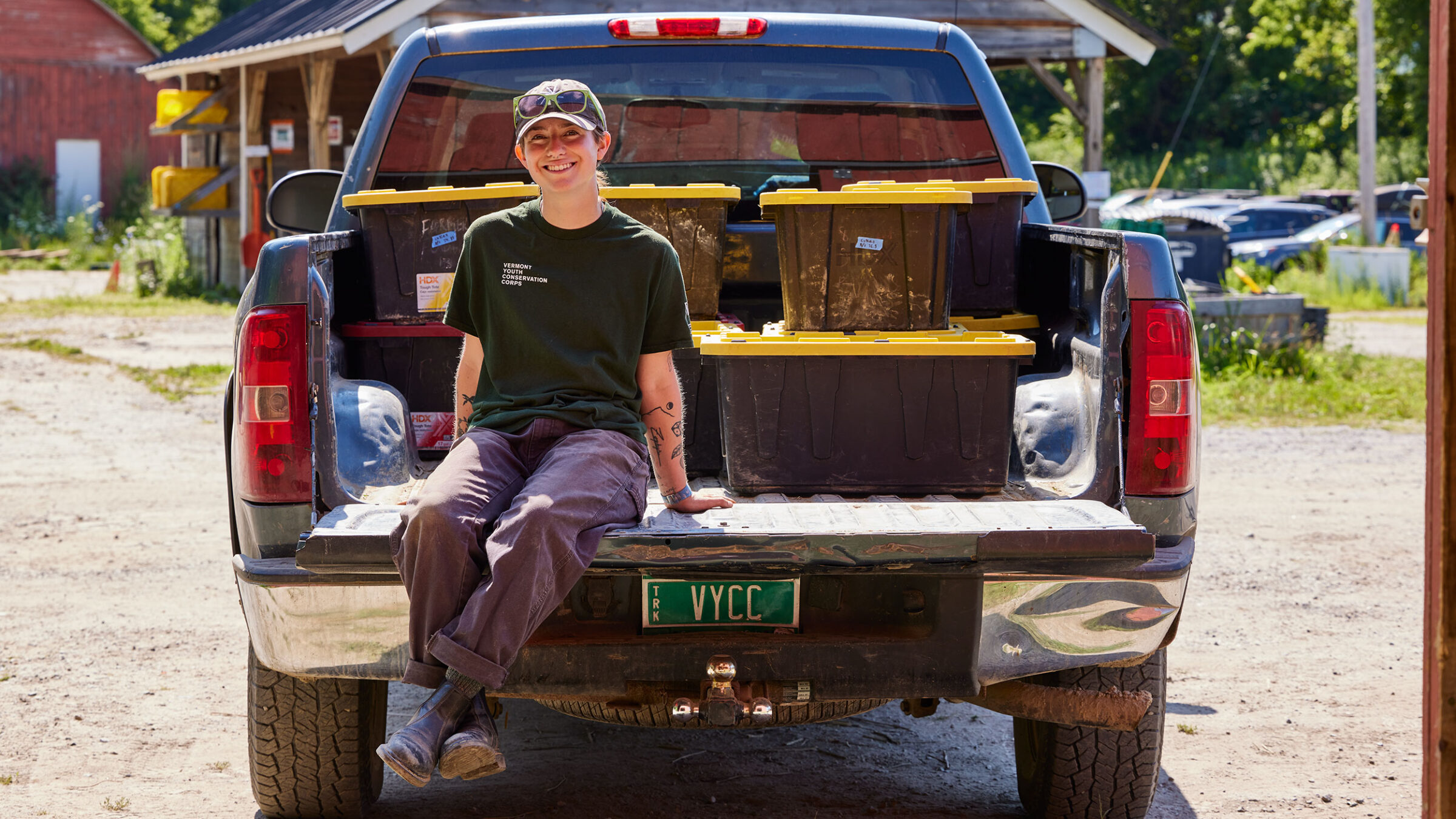 Morgan Chesnais sits on the bed of a pickup truck at their internship at an 11-acre farm owned by VYCC.