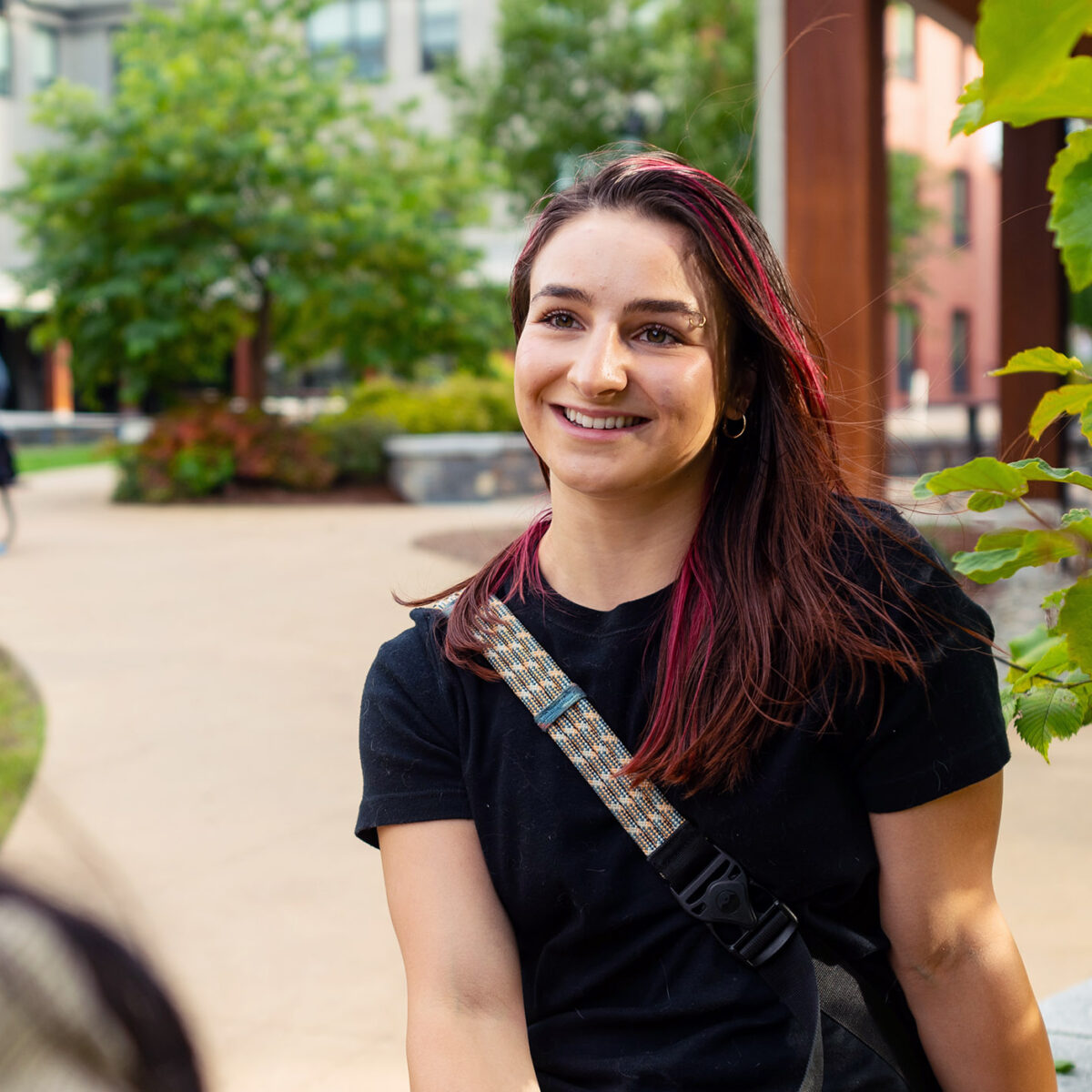 student listens to another student off screen; located in an outdoor area