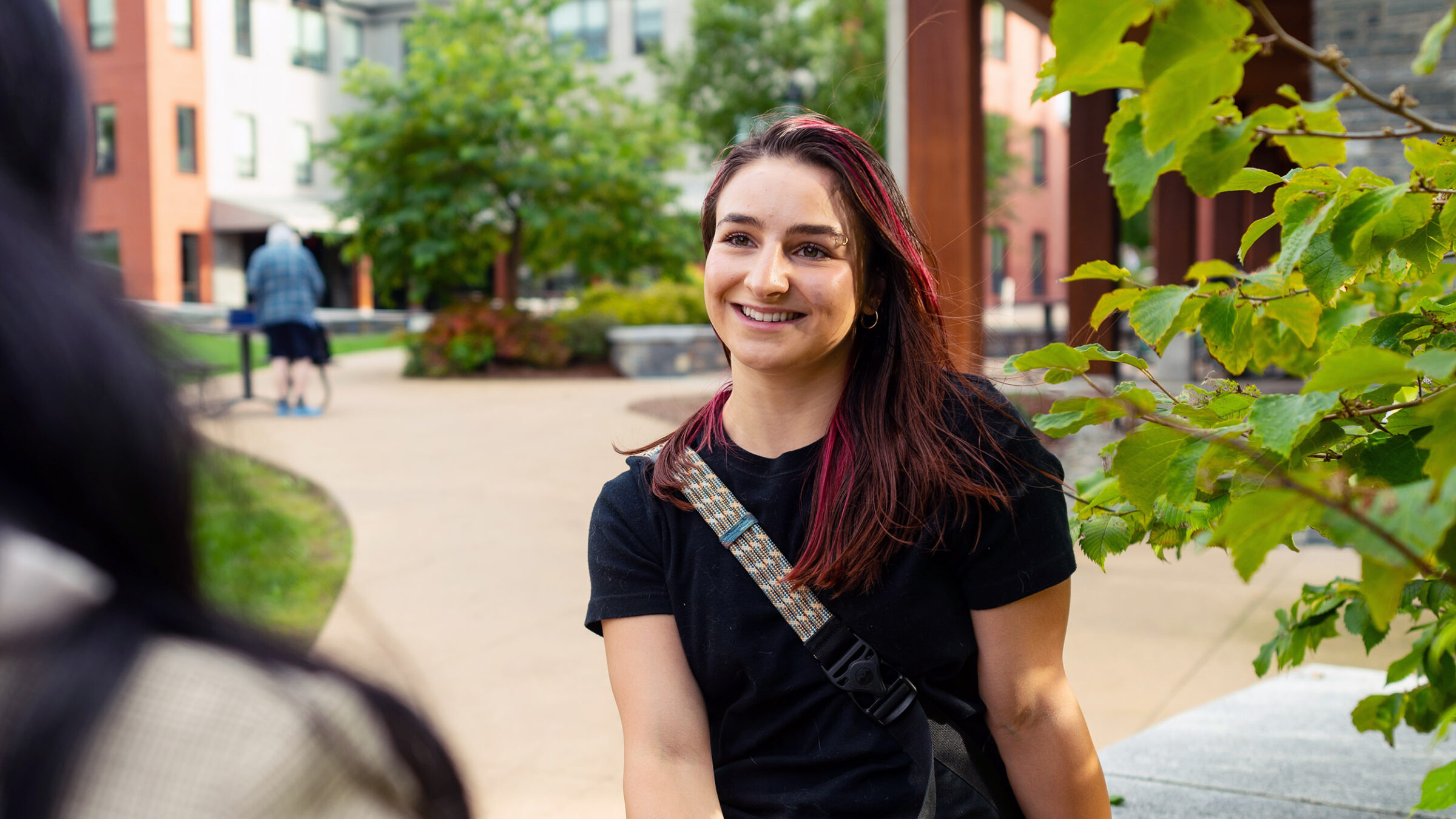 student listens to another student off screen; located in an outdoor area
