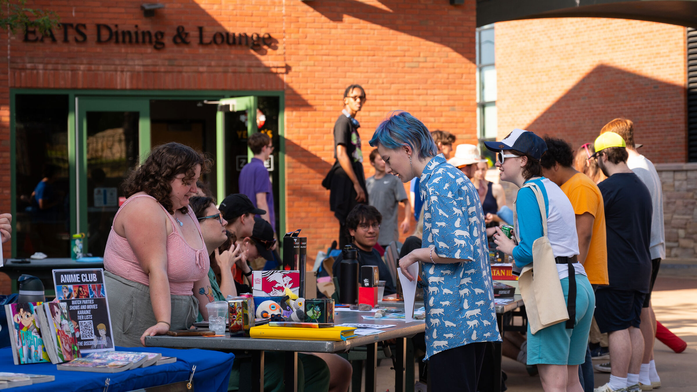 students talking to one another across a table in a crowded courtyard