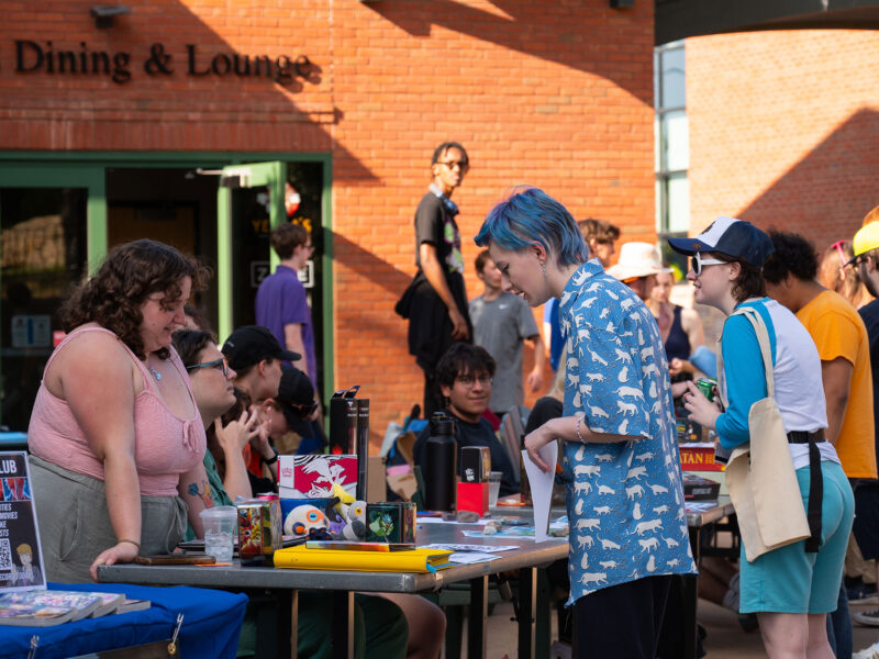 students talking to one another across a table in a crowded courtyard