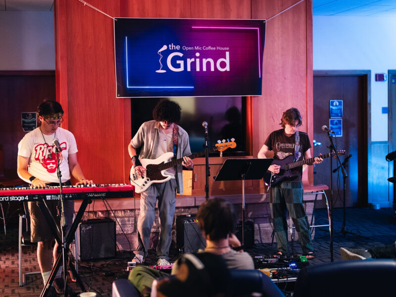 three students perform music at the grind