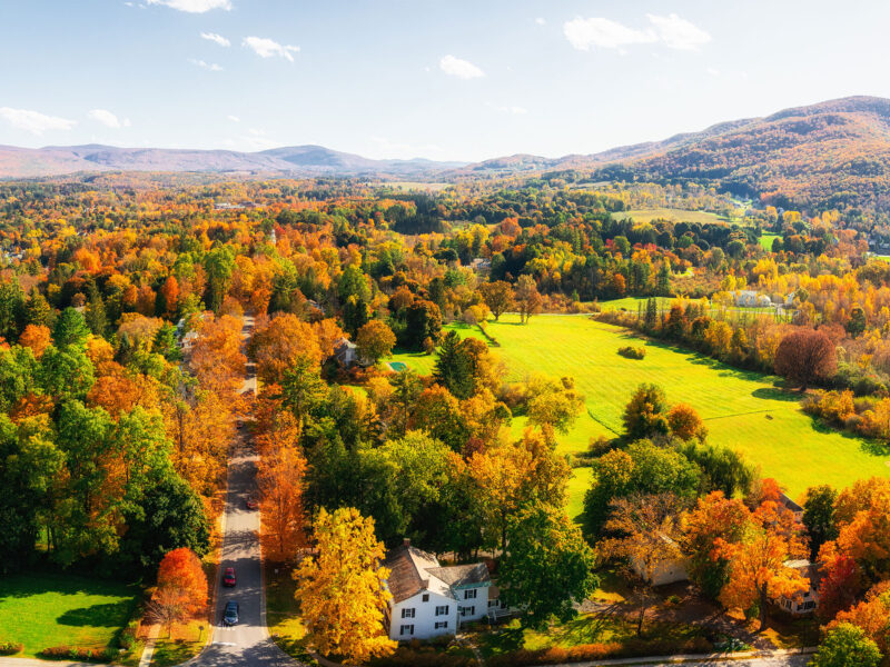 foliage landscape in vermont with mountains. orange, yellow, and red leaves on trees