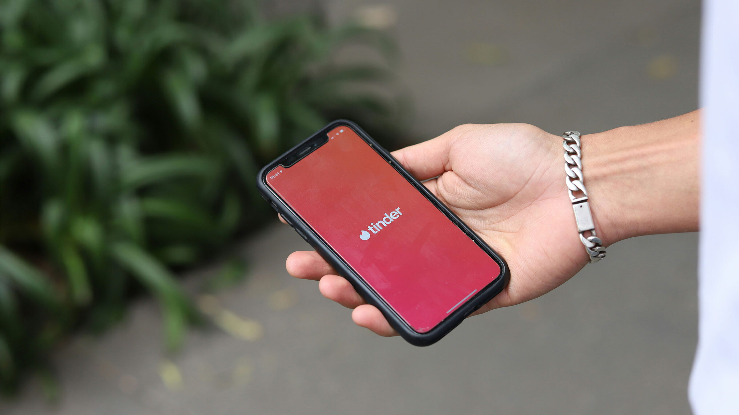 person's hand holding a phone with the tinder app open