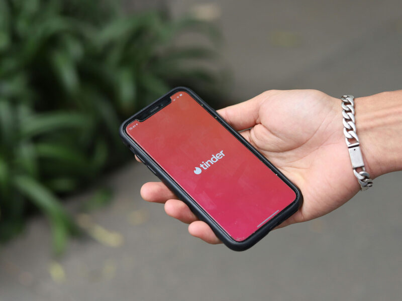 person's hand holding a phone with the tinder app open