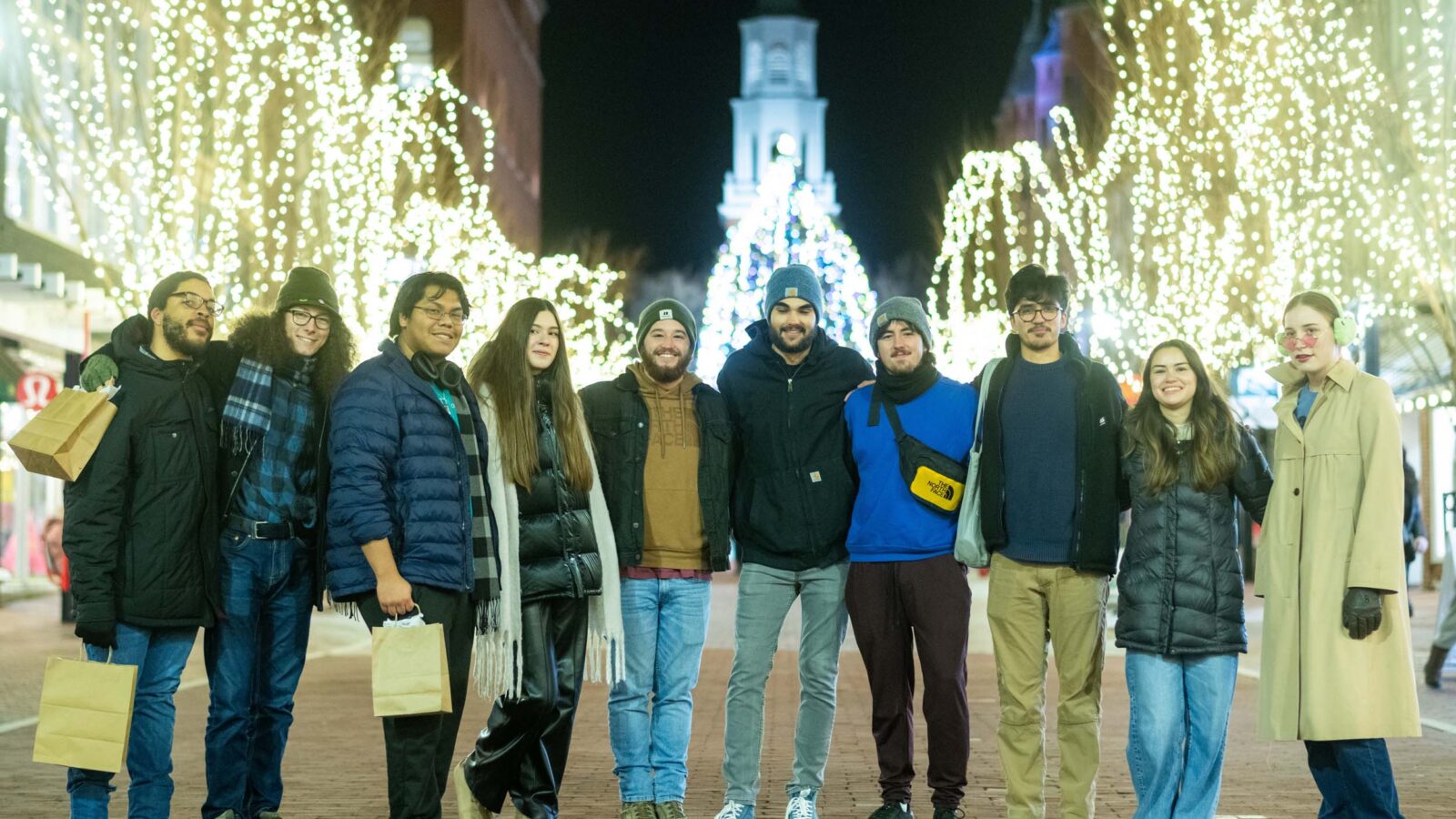 Students posing on Church Street in front of the lit Christmas Tree