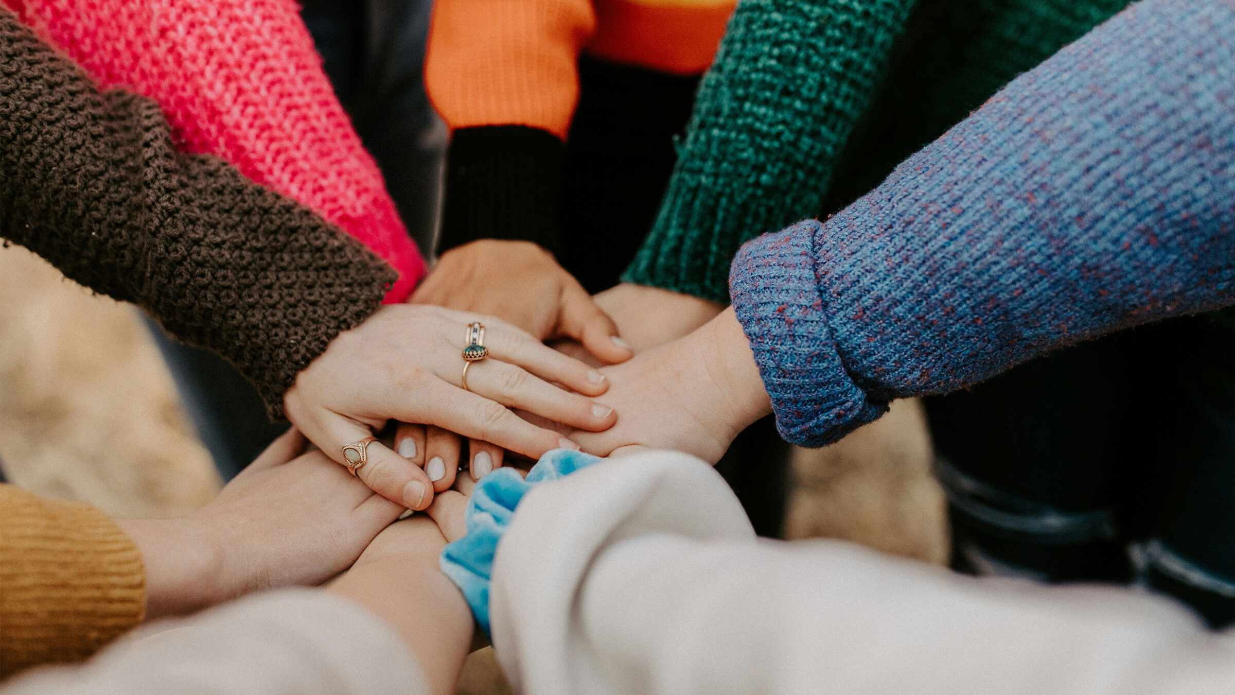 5+ people putting their hands together in a circle