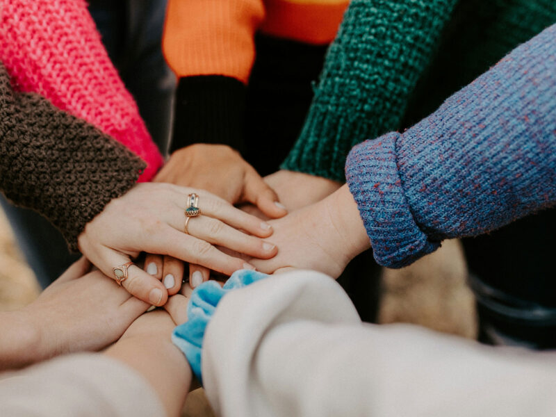 5+ people putting their hands together in a circle