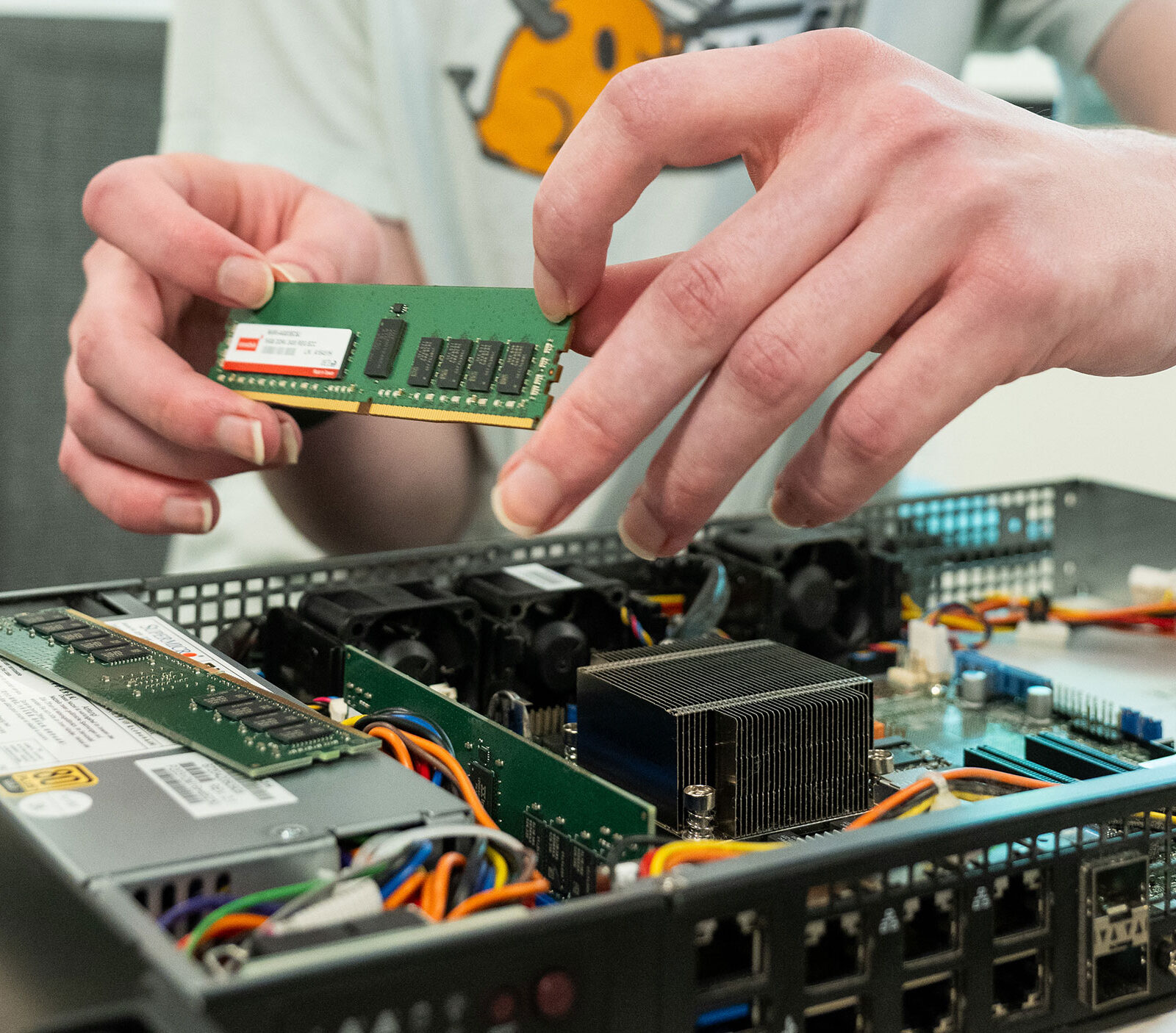 A student handles a computer chip as they reassemble a server.