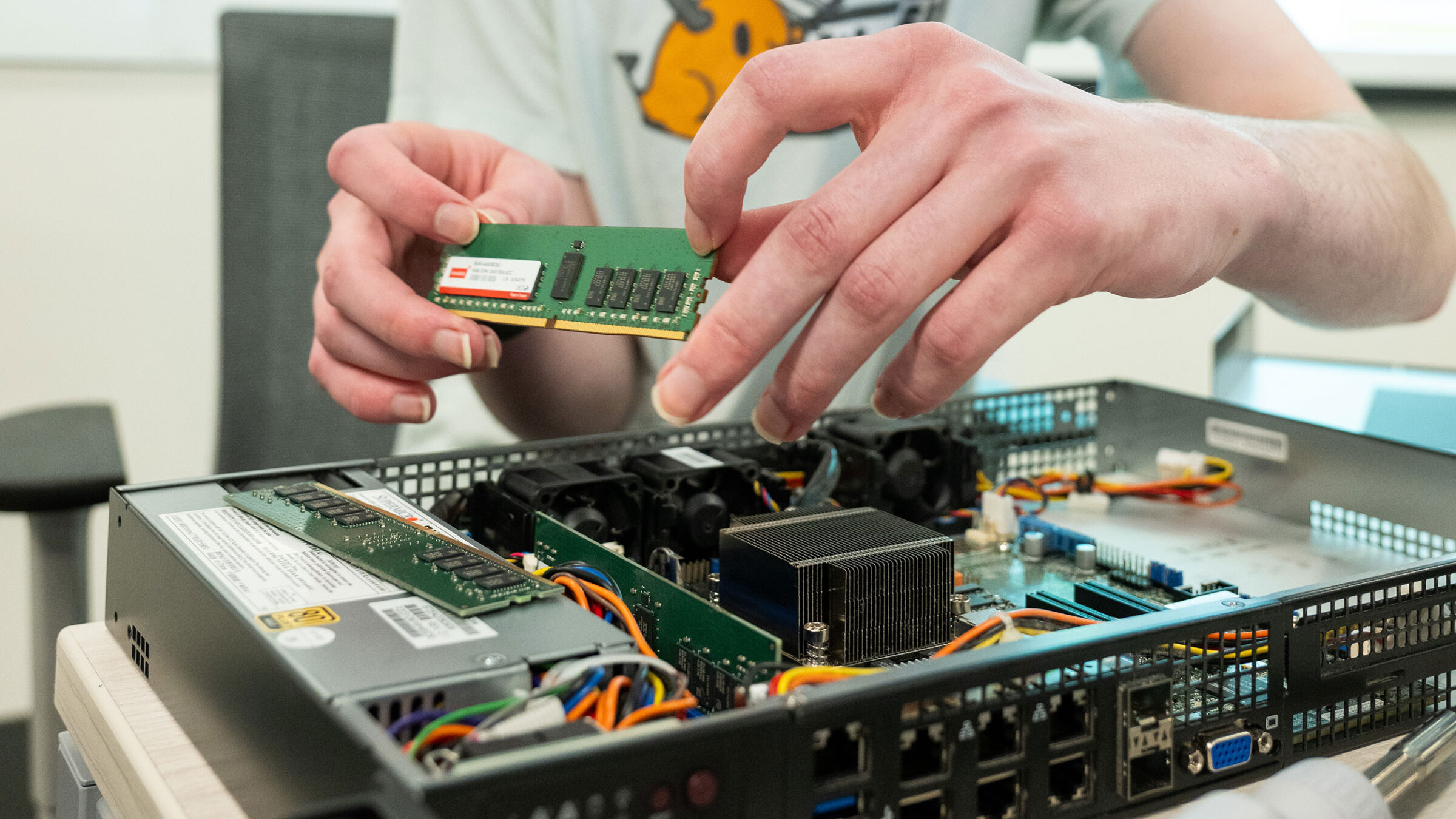 A student handles a computer chip as they reassemble a server.