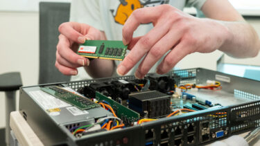 A student handles a computer chip as they reassemble a server.