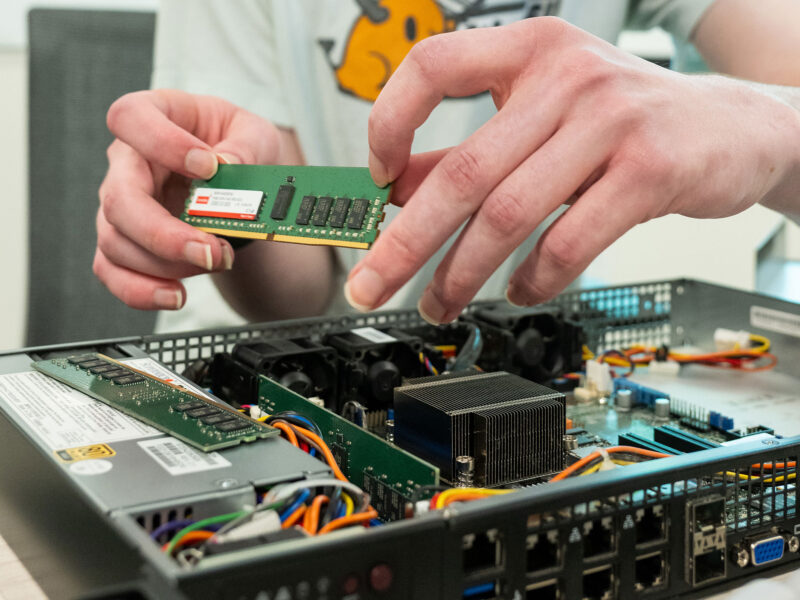 A student handles a computer chip as they reassemble a server.