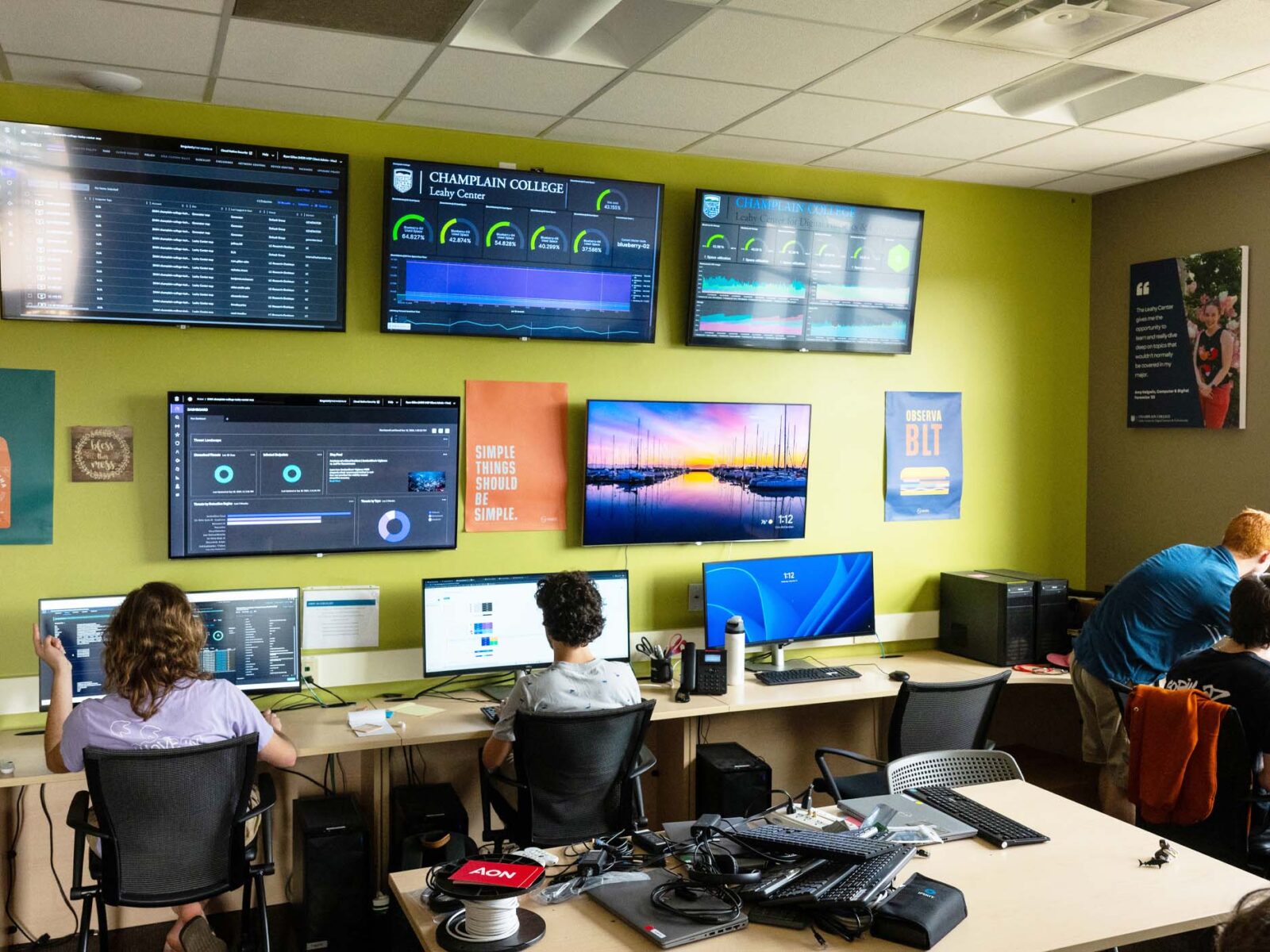 students working in the Leahy Center on computers with monitors on a green wall with bright light from the windows