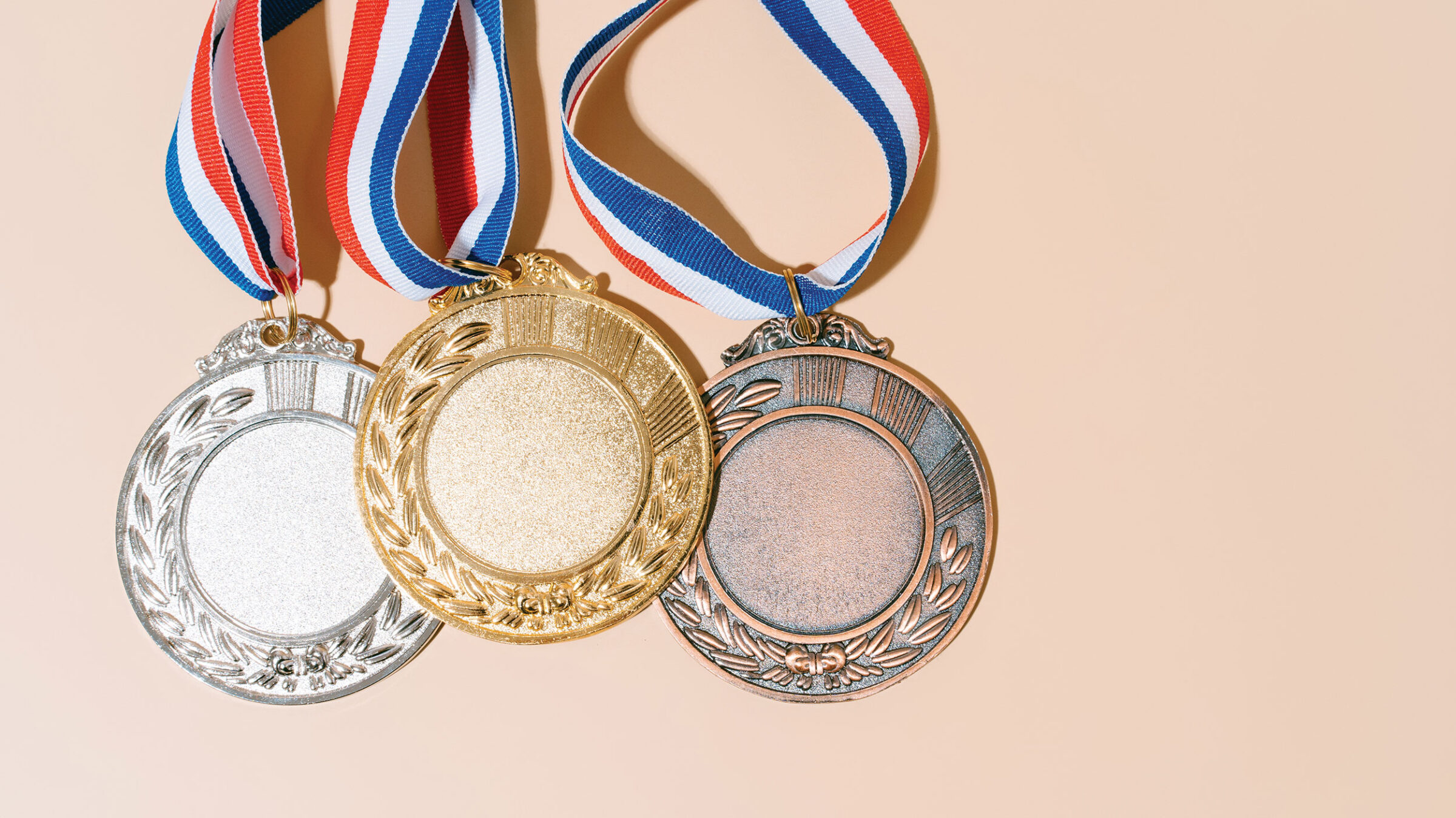 silver, gold, and bronze medals against a peach-colored background