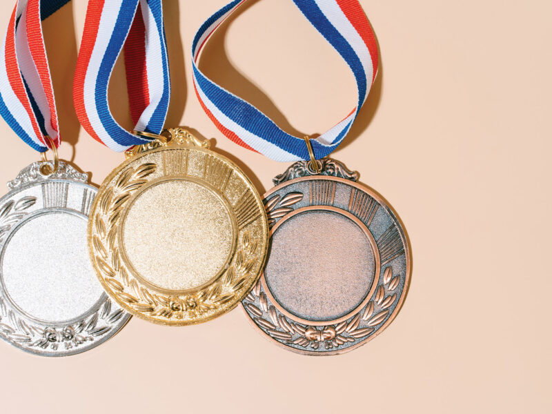 silver, gold, and bronze medals against a peach-colored background