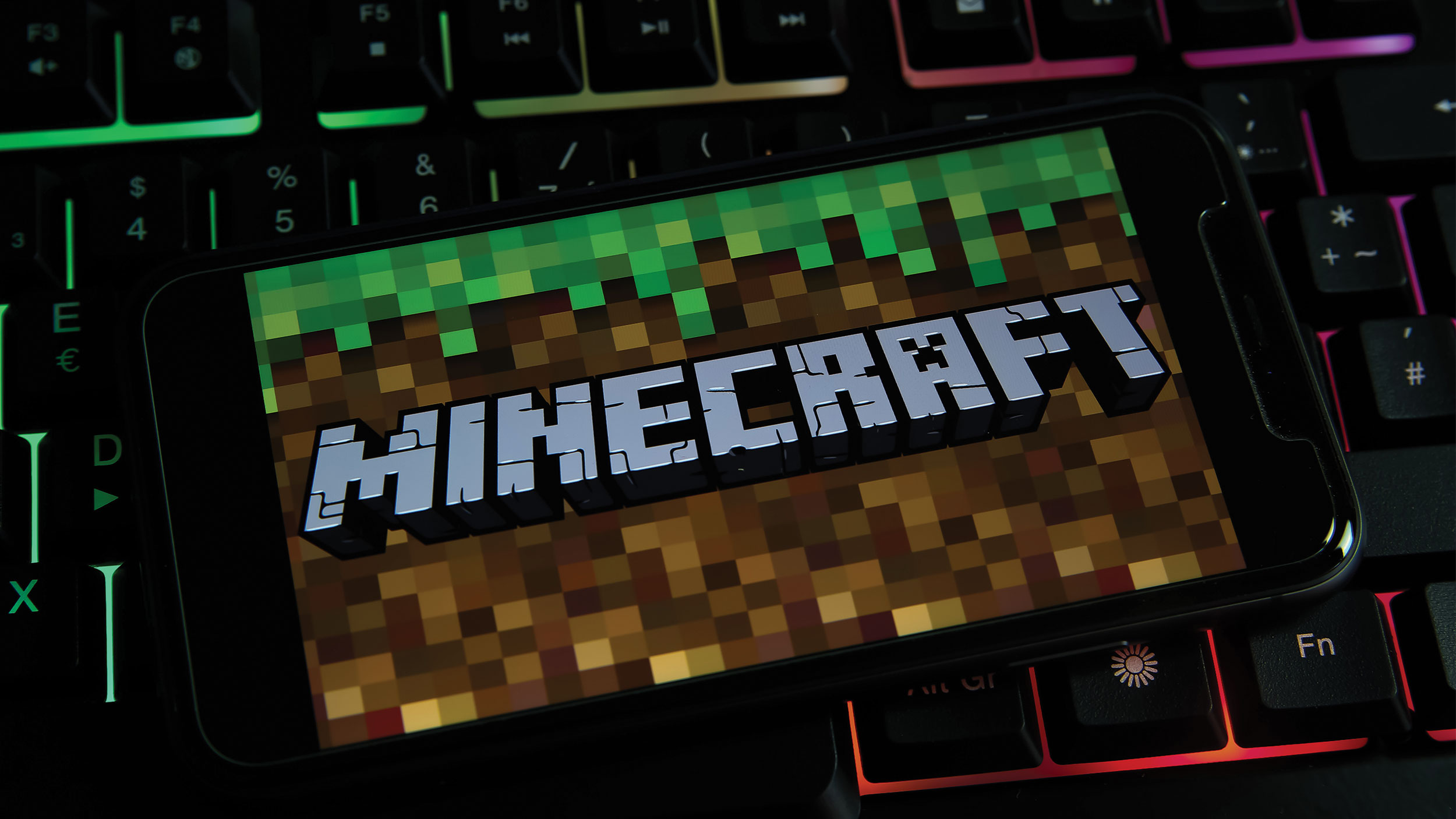 minecraft game opens on a phone atop a rainbow keyboard
