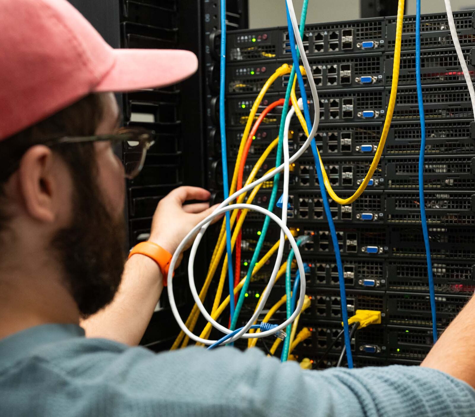 Student organizing colored wires in the back of a server