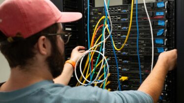 Student organizing colored wires in the back of a server