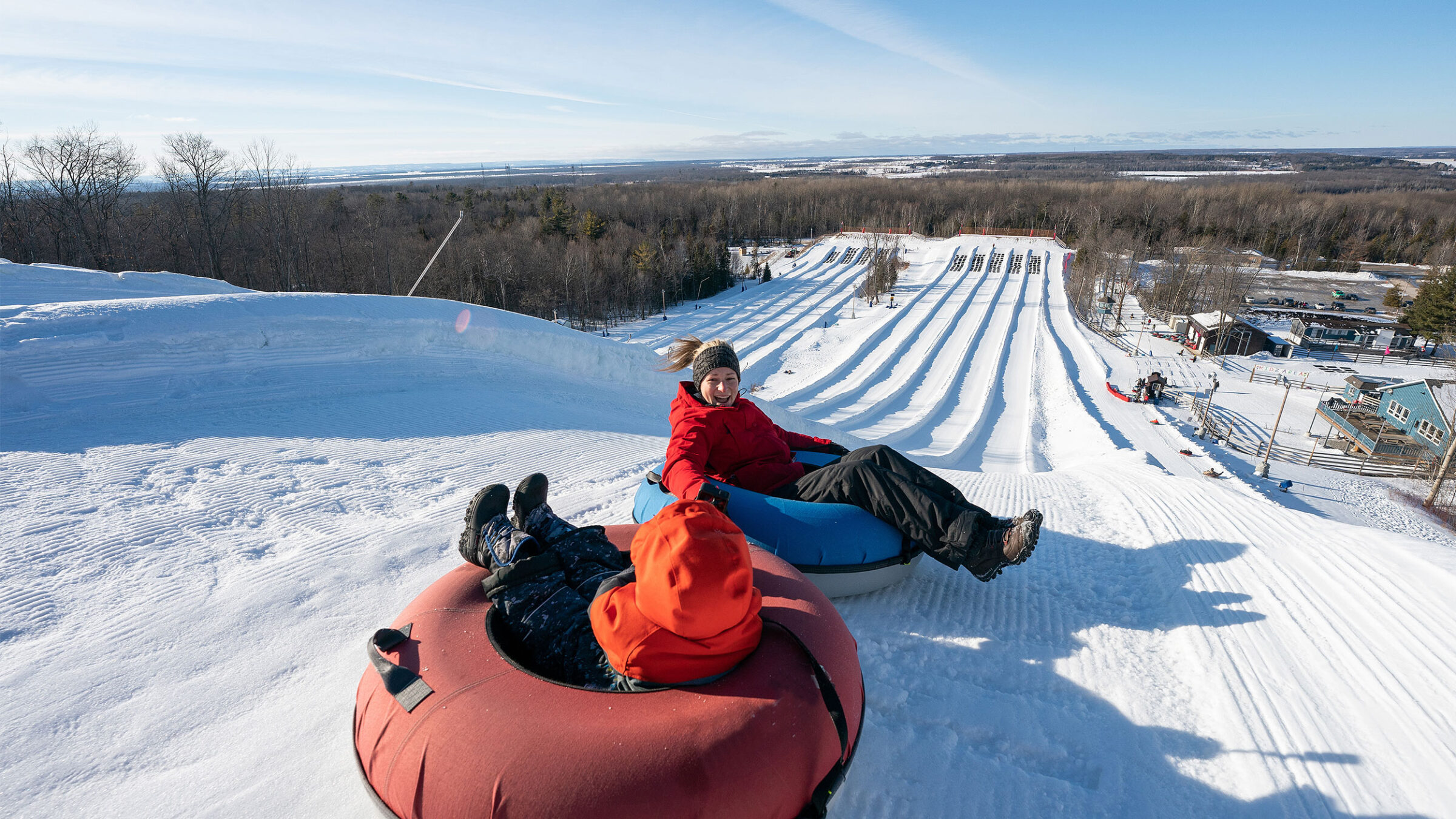 two people tubing down snowy resort trail