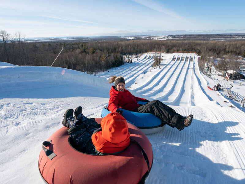 two people tubing down snowy resort trail