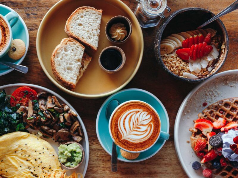 a breakfast feast is arranged on a wooden table