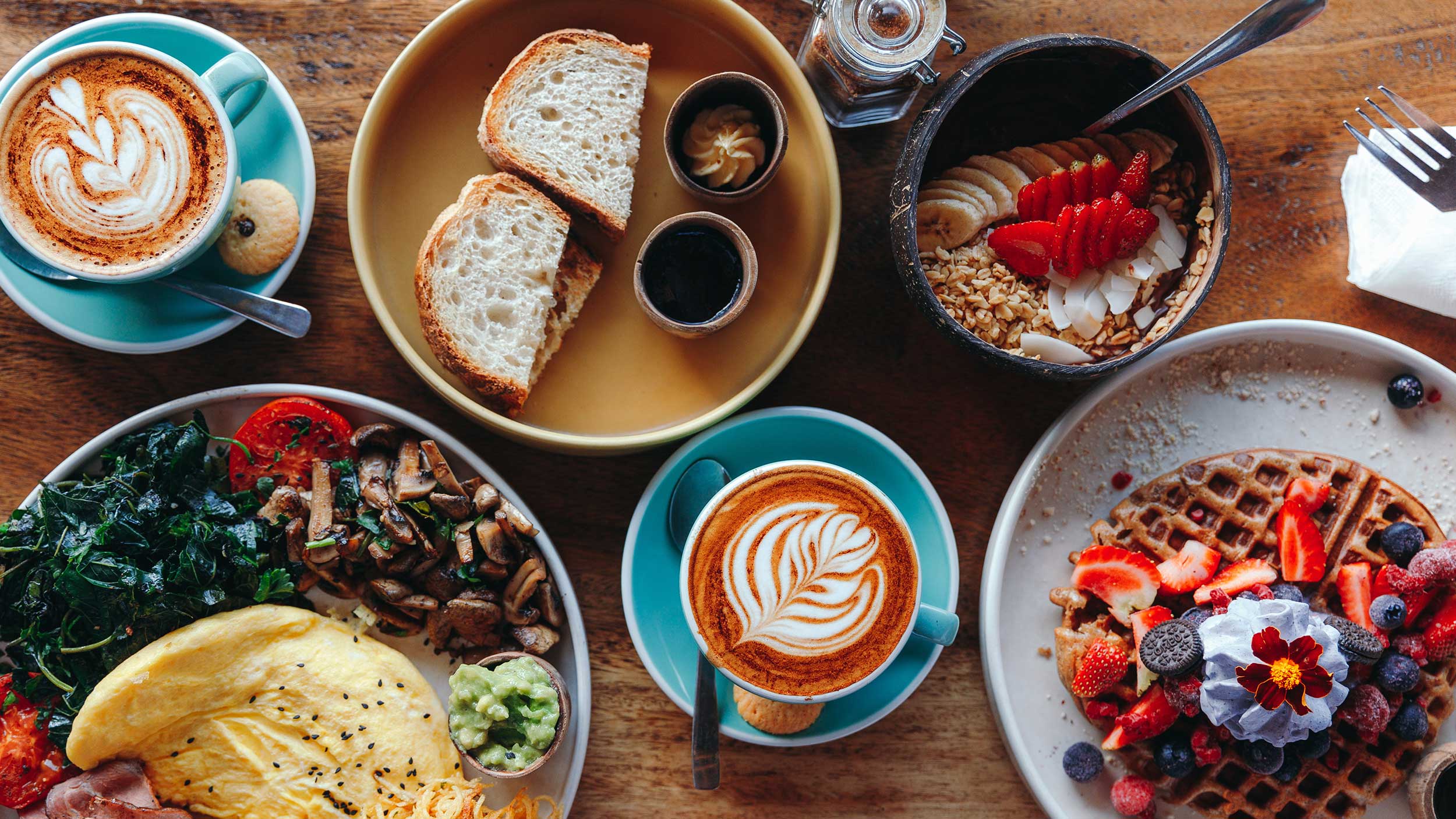 a breakfast feast is arranged on a wooden table