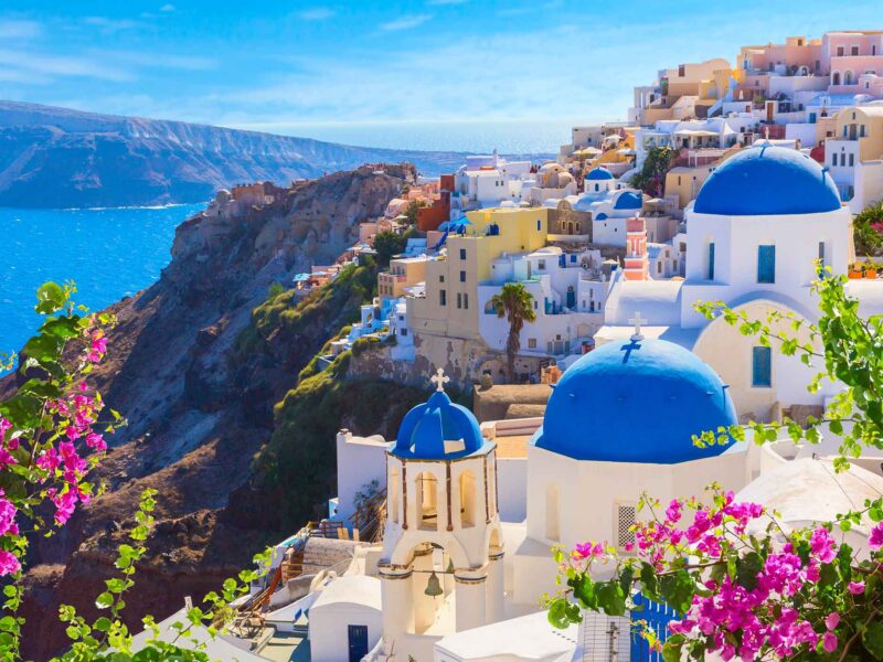 a vibrant scene of a city in greece built into the rocky coast