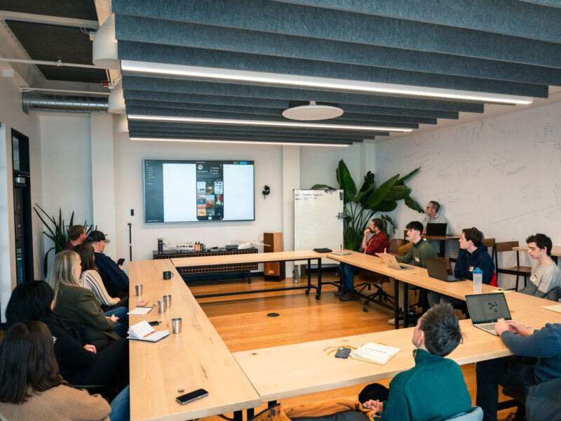 Students presenting at a conference with people around a large table