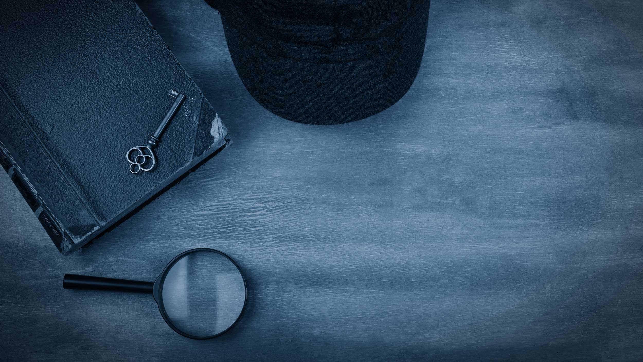 black and white image of a notebook, key, hat, and magnifying glass